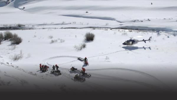 People reach injured person with helicopter and snowmobile