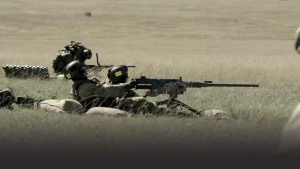 Commandos shooting large machine gun in field