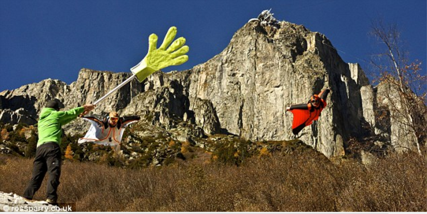 A wingsuit pilot fro the BASE Crew gives a proximity flight high five Wingsuit pilot gives a high five
