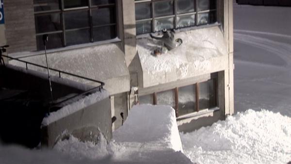 snowboarder jumping off a ramp onto an office building