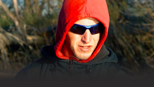 A crew member stands with his hood on.