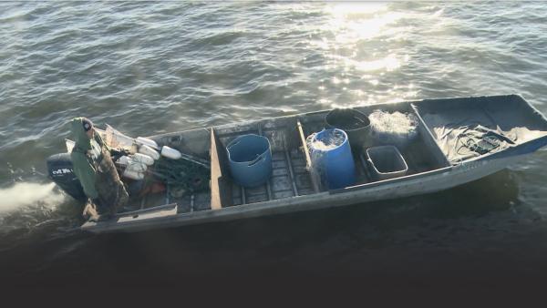 A man drives a fishing boat in the water.