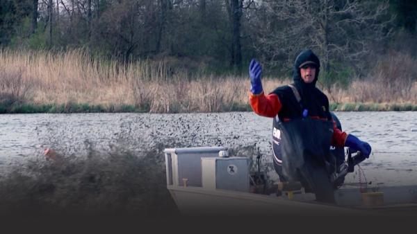A fisherman stands in a boat.