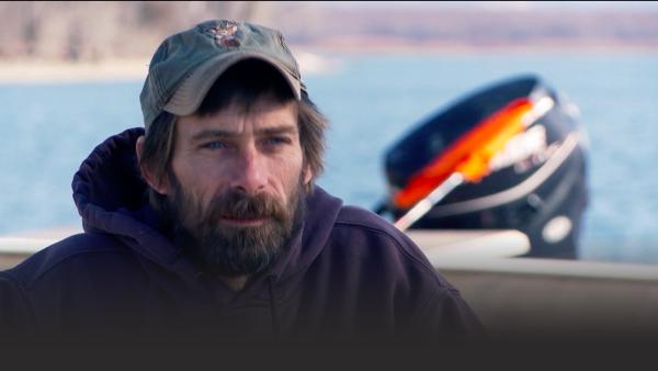 A crew member sits on a boat.