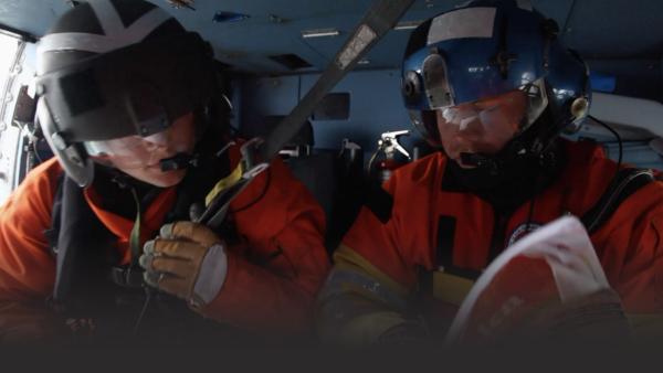 Men in a helicopter looking at maps
