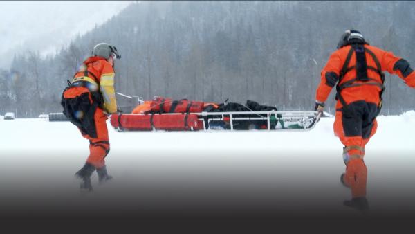 Two people carrying a stretcher.