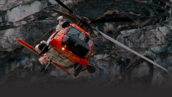 Helicopter swooping by cliff