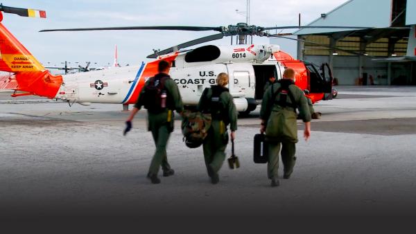 Three medics walk towards a helicopter