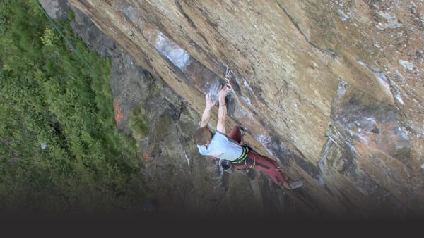 Man hangs high above ground on sheer rock face