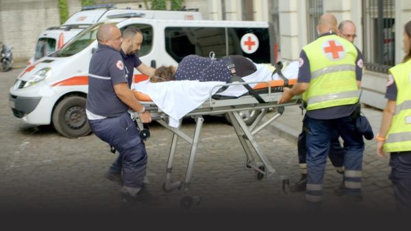 EMTs pushing a woman on a stretcher