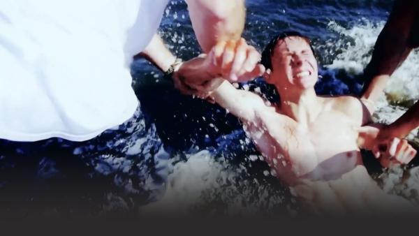 Man being dragged from the ocean while in pain 