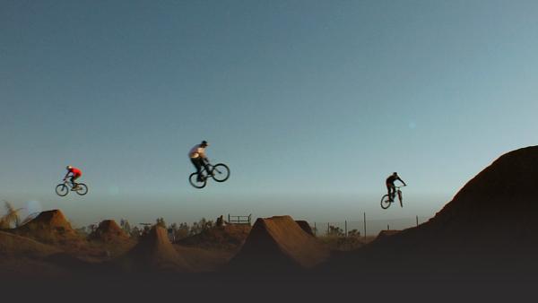 Three different bikers all midair over dirt bike course