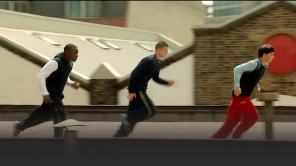 Three men run on a roof