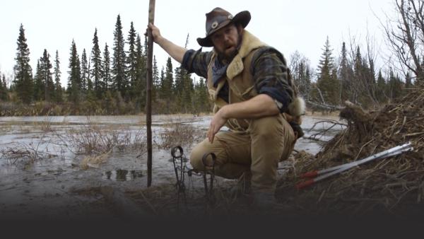 Man with a stick near some mud