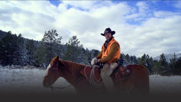 A hunter on a horse waits in a snowy forest.