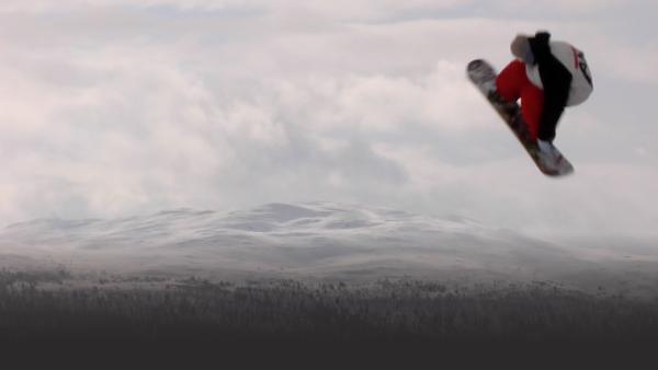 snowboarder suspended high in air with mountains in background